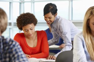 Teacher helping older female student read